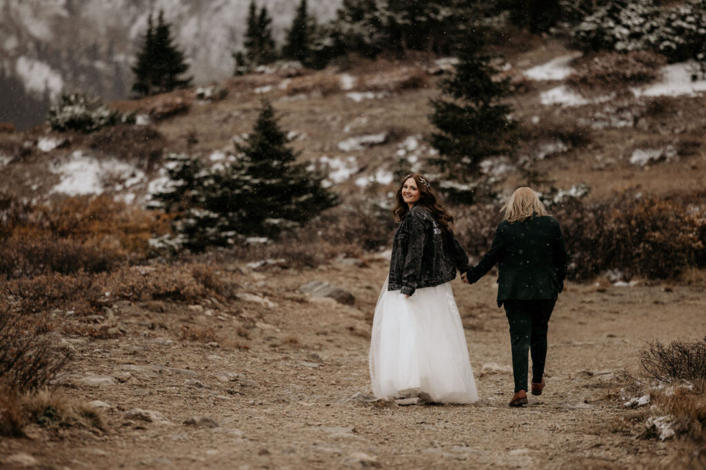 newlywed couple walks along snowy trail during their elopement ceremony.