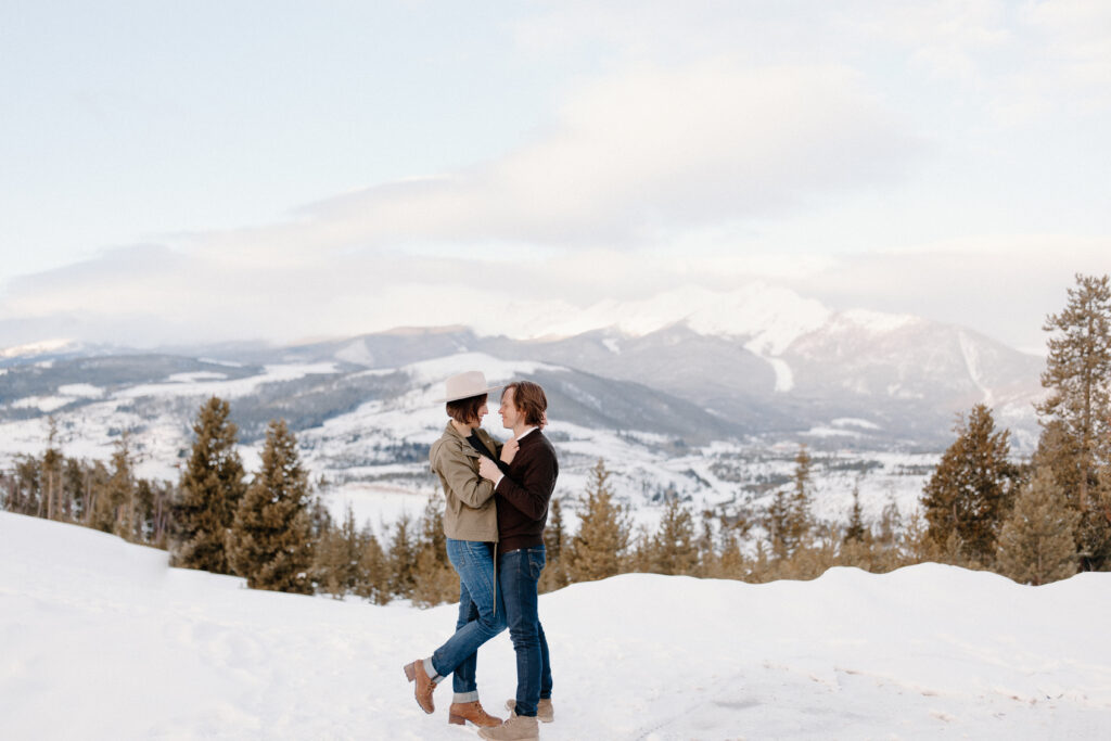 man and woman stand in front of the colorado mountains during engagement photos at Sapphire Point.