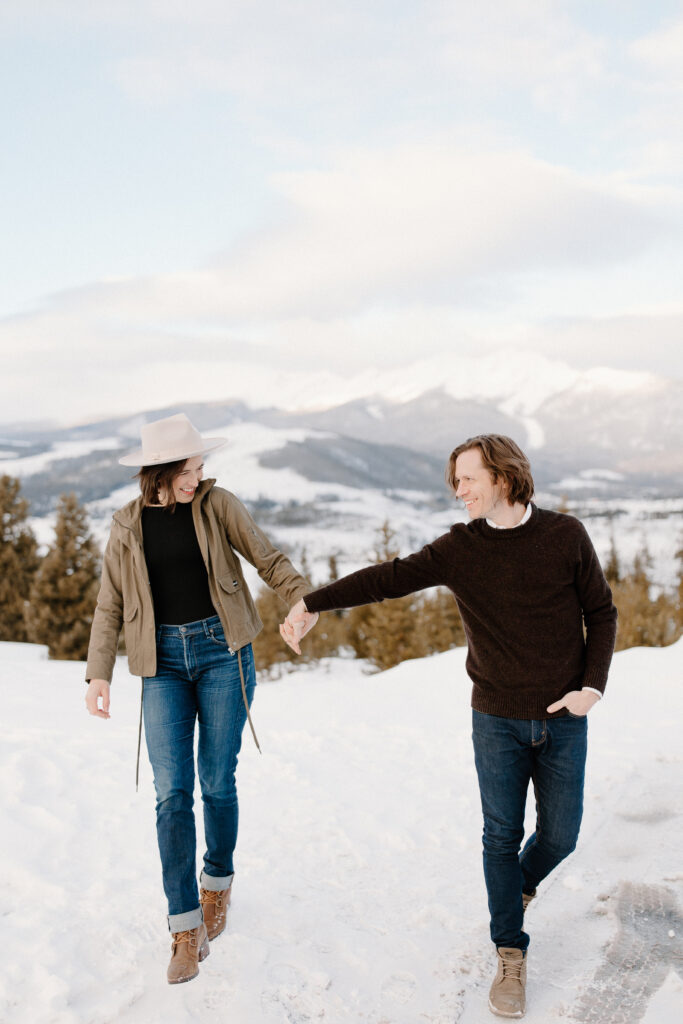 mand and woman hold hands during engagement photos in the colorado mountains.