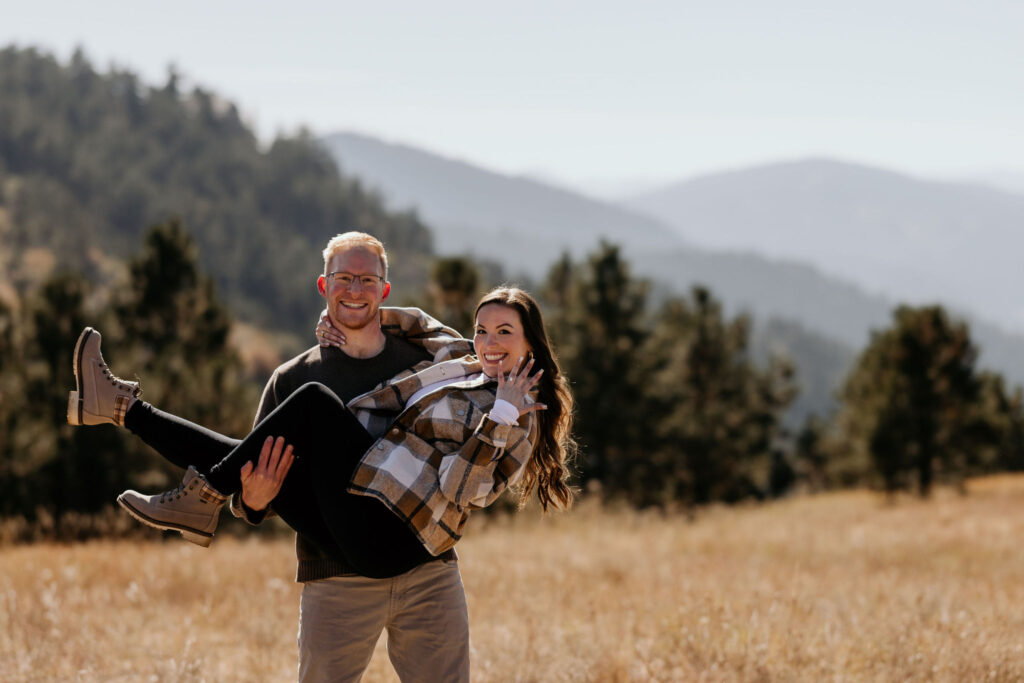 man picks up woman and carries her during colorado proposal photos.