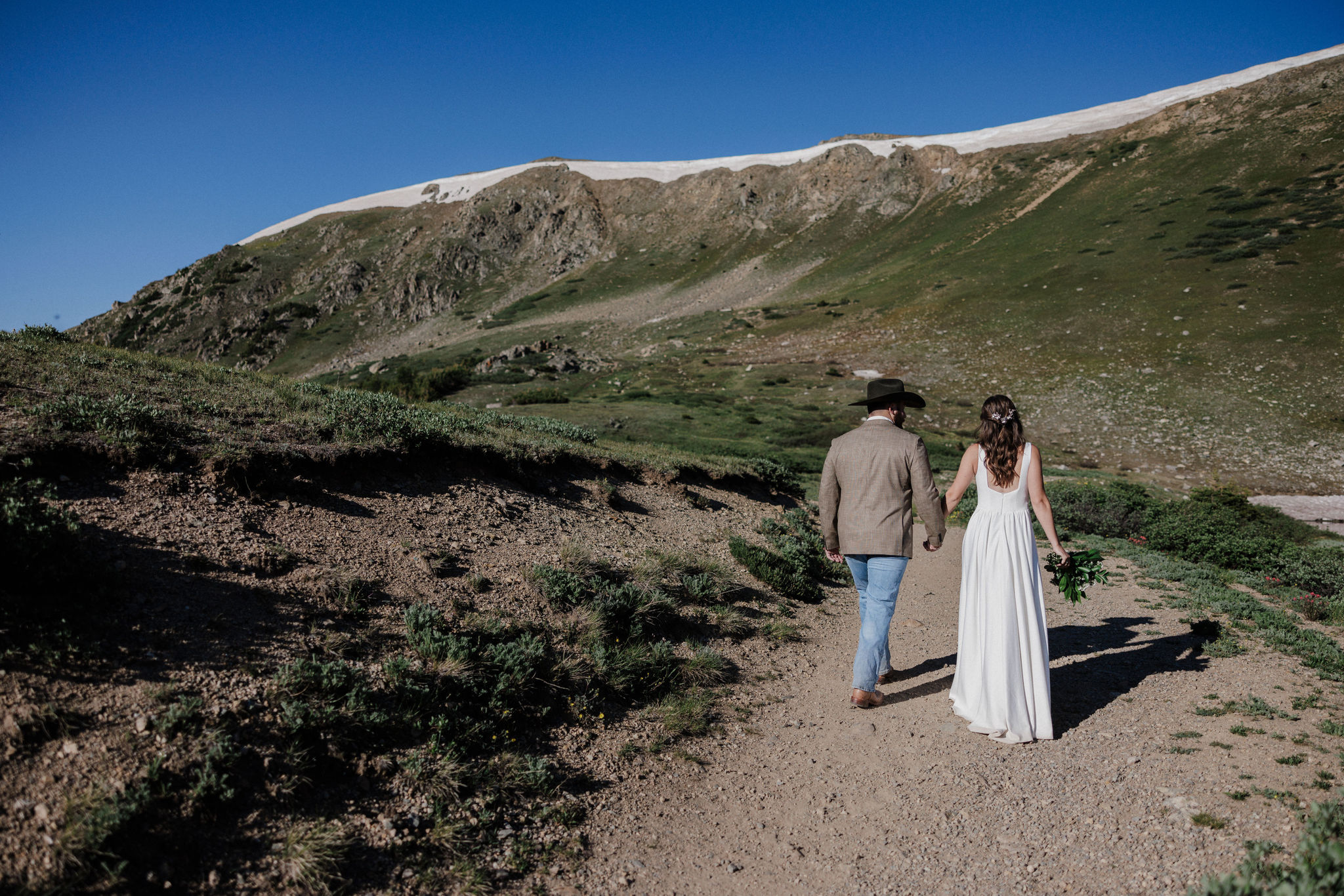 bride and groom walk along trail at colorado elopement location