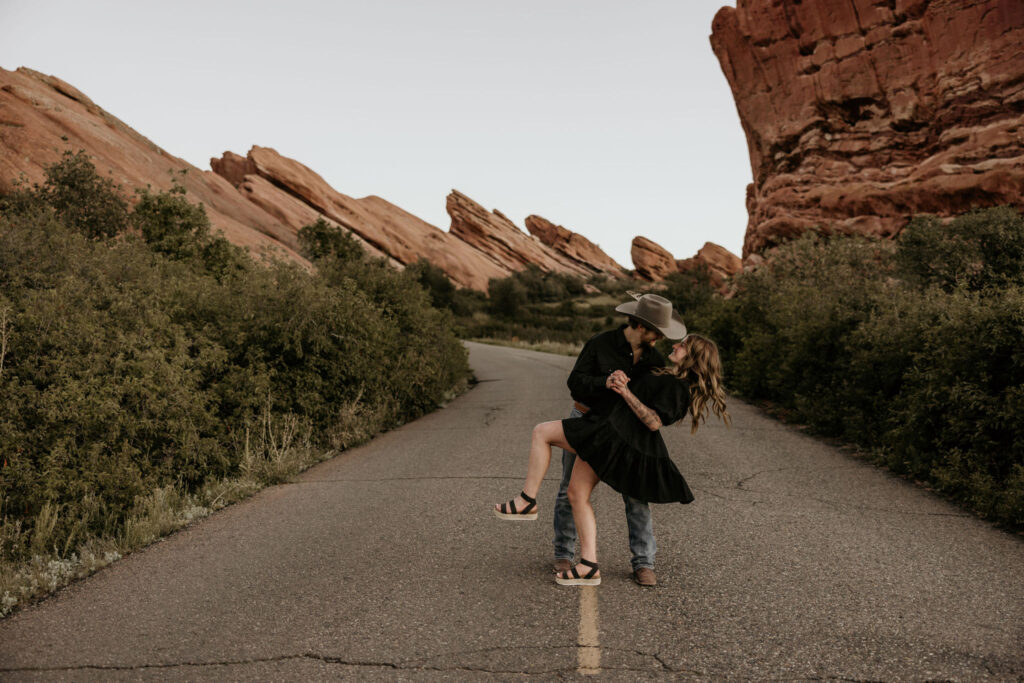 man dips and kisses woman during their colorado portrait session at red rocks park & amphitheatre.