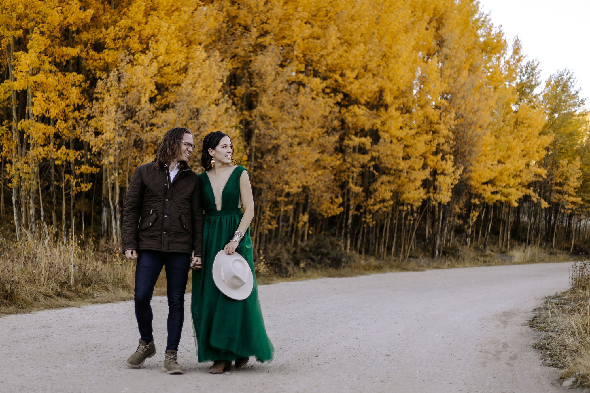 man and woman stand in front of yellow aspen trees