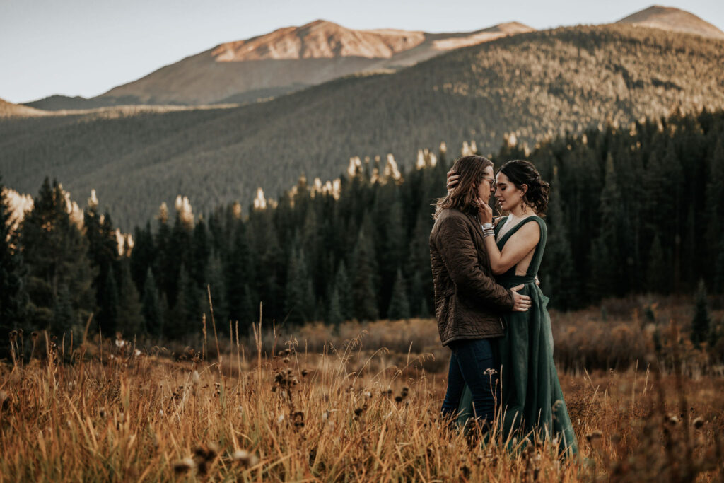 man and woman stand in front of colorado mountains during sunset portraits.