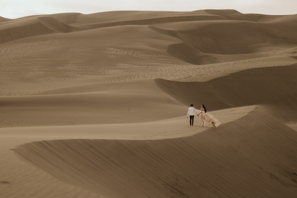couple walks along great sand dunes national park during portrait session.