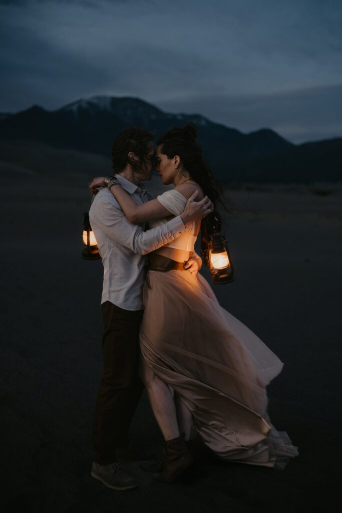 man and woman embrace with lanterns during night portraits in colorado.