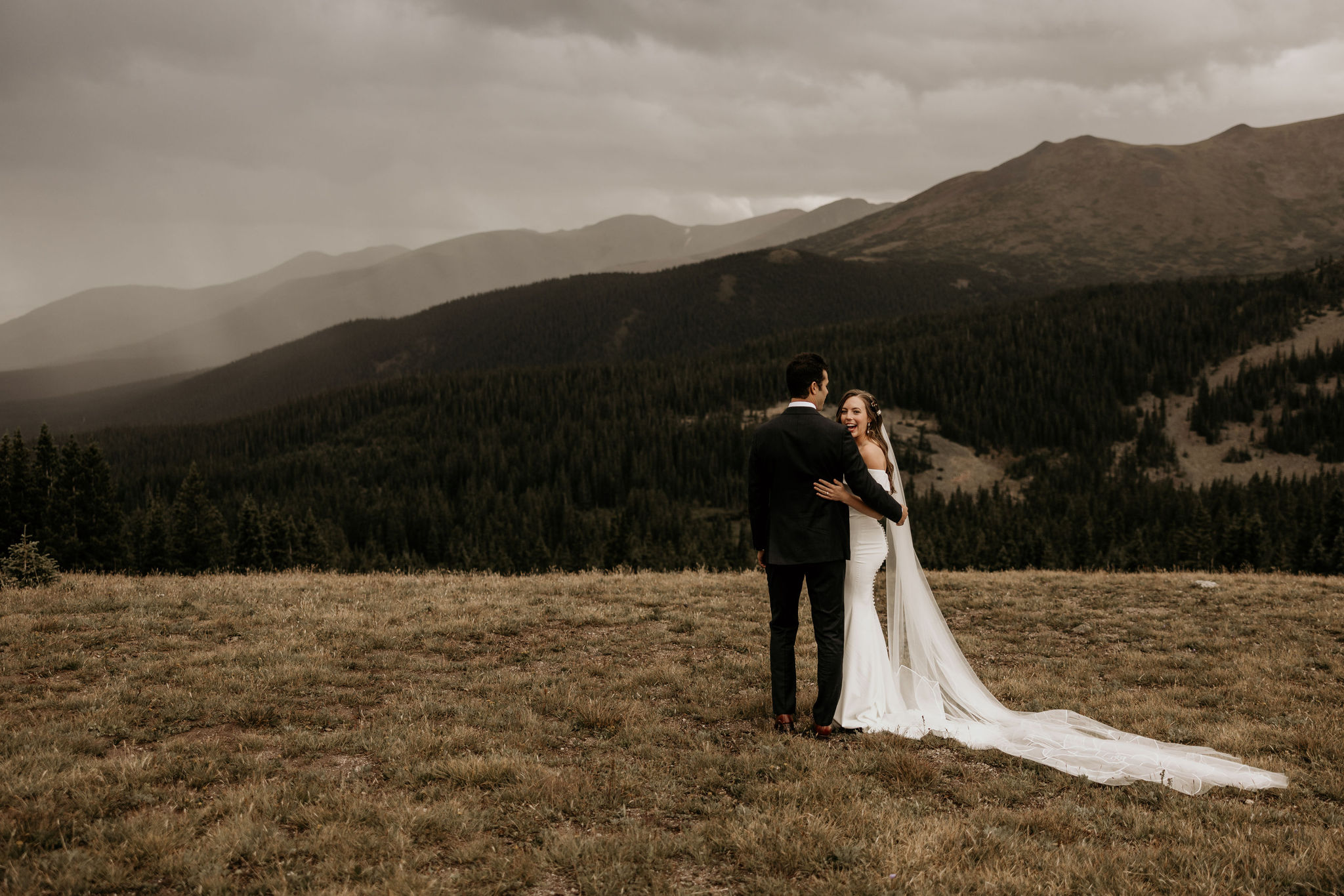 bride and groom embrace and look out at the colorado mountains during elopement day.