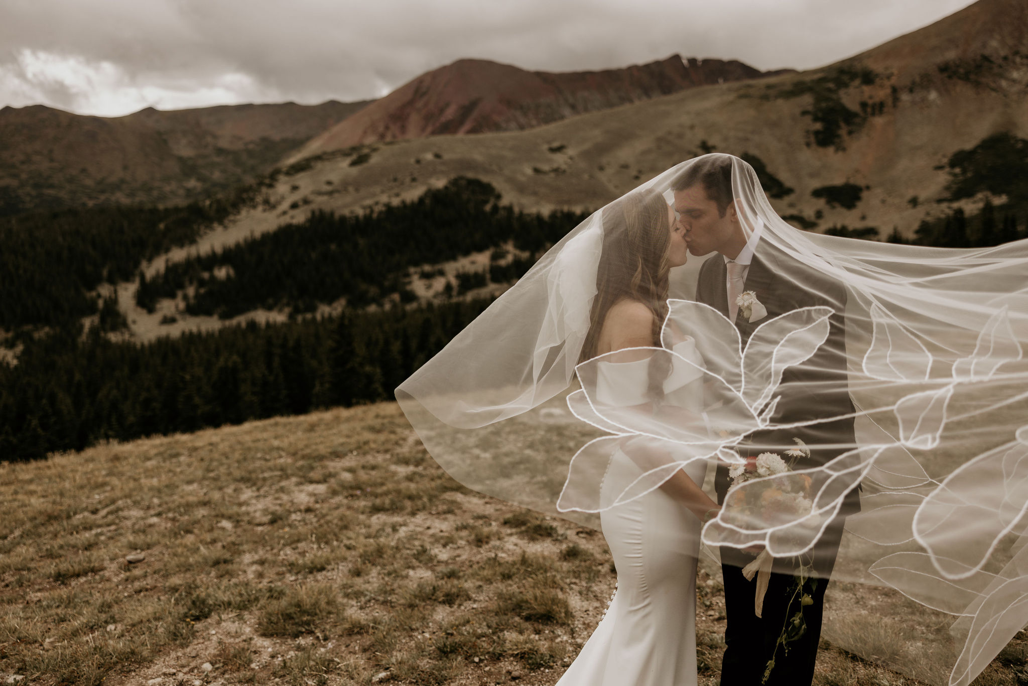 bride and groom kiss under veil during stress free wedding day.