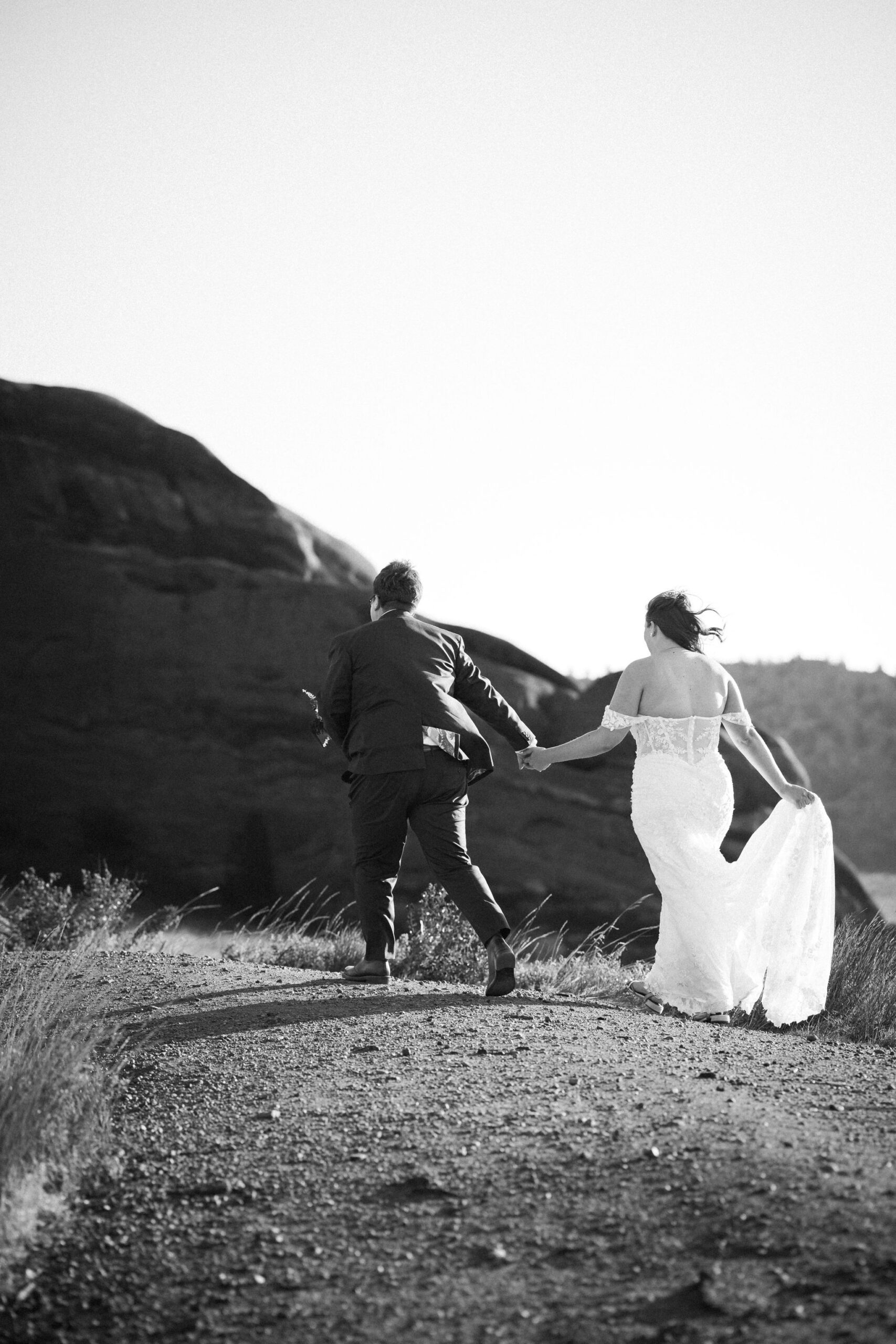 two brides hold hands and walk along trail at colorado wedding location