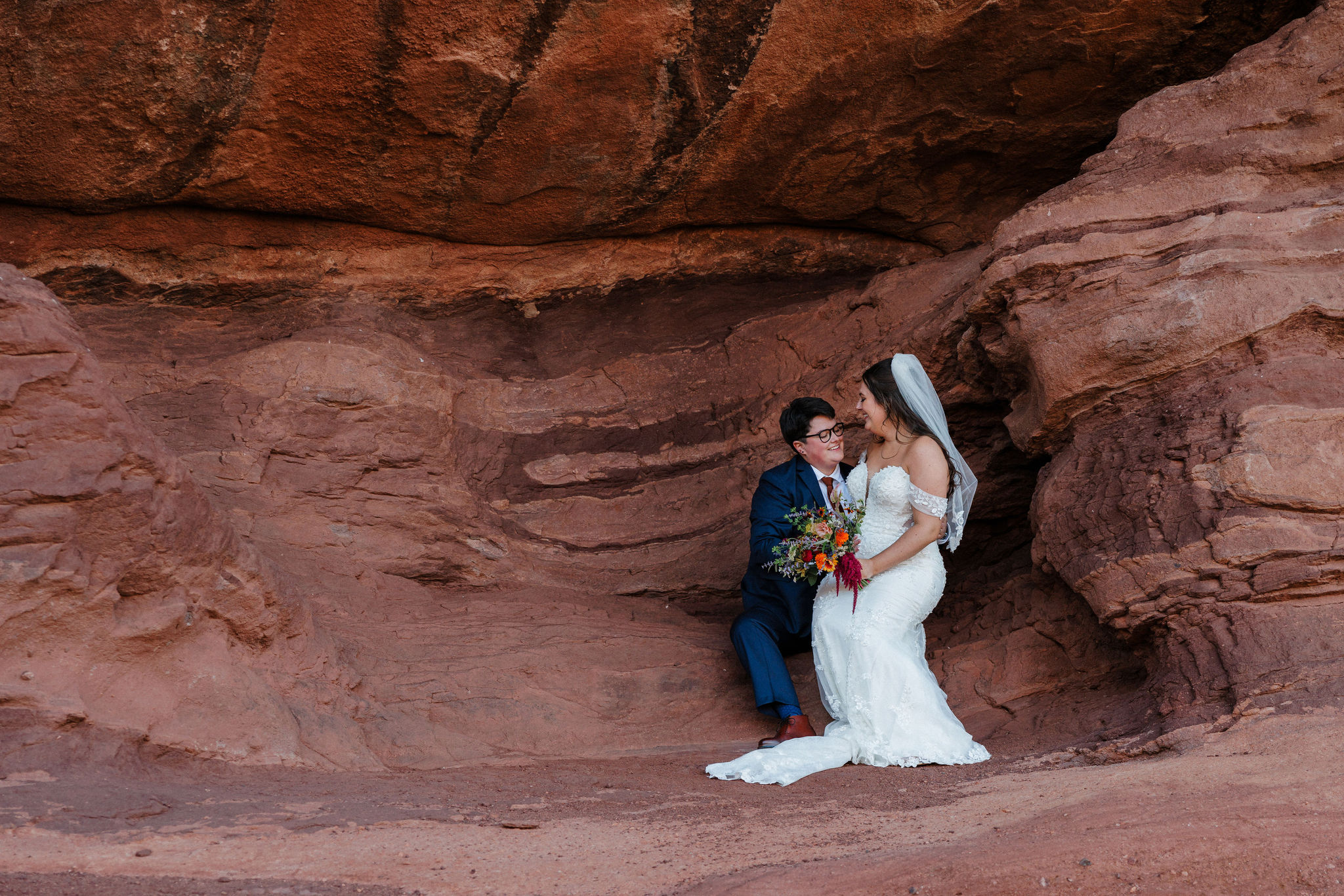 lgbtq+ couple sits on the rocks at red rocks amphitheater