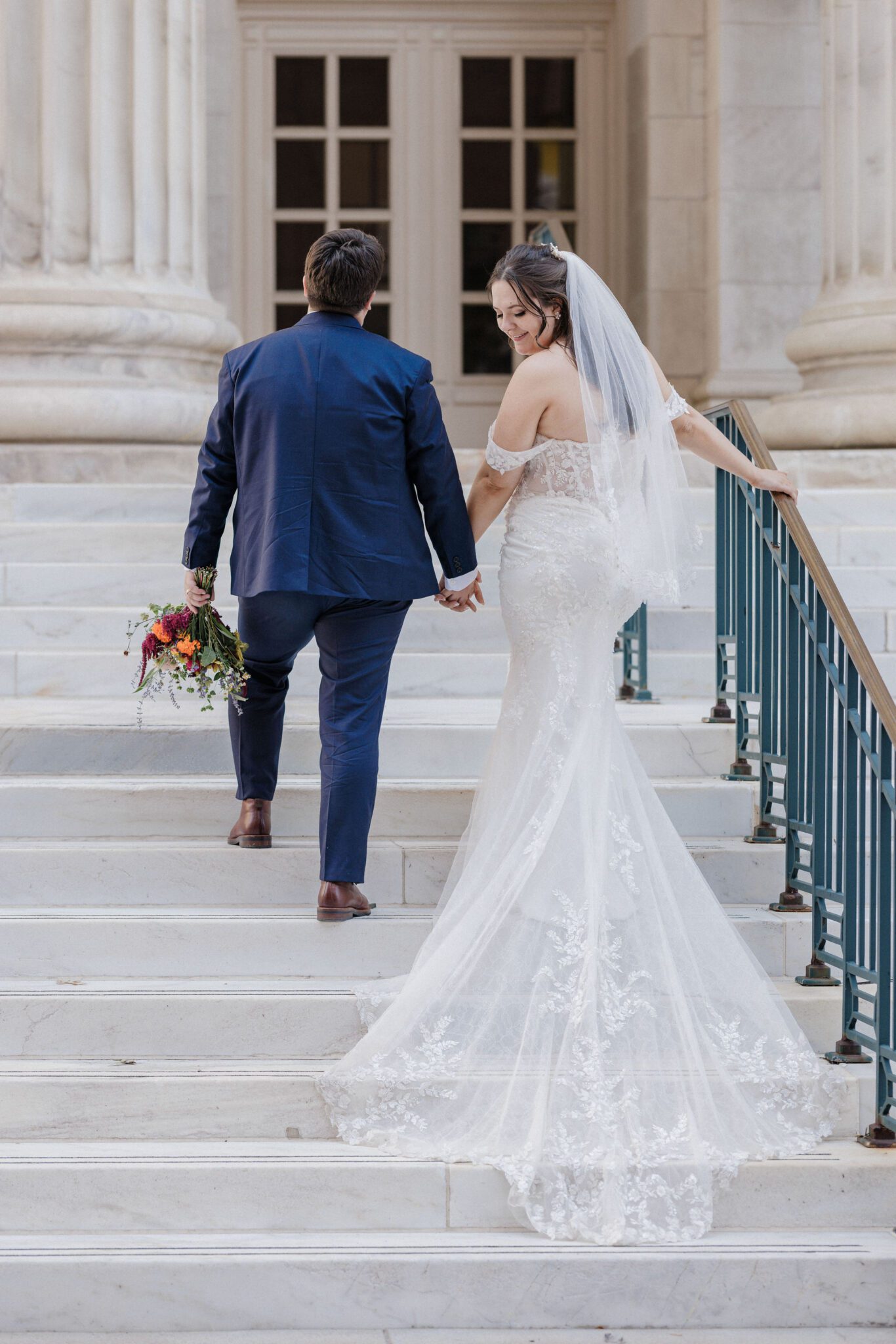 a couple stands in front of a window at byron white courthouse during engagement photos.