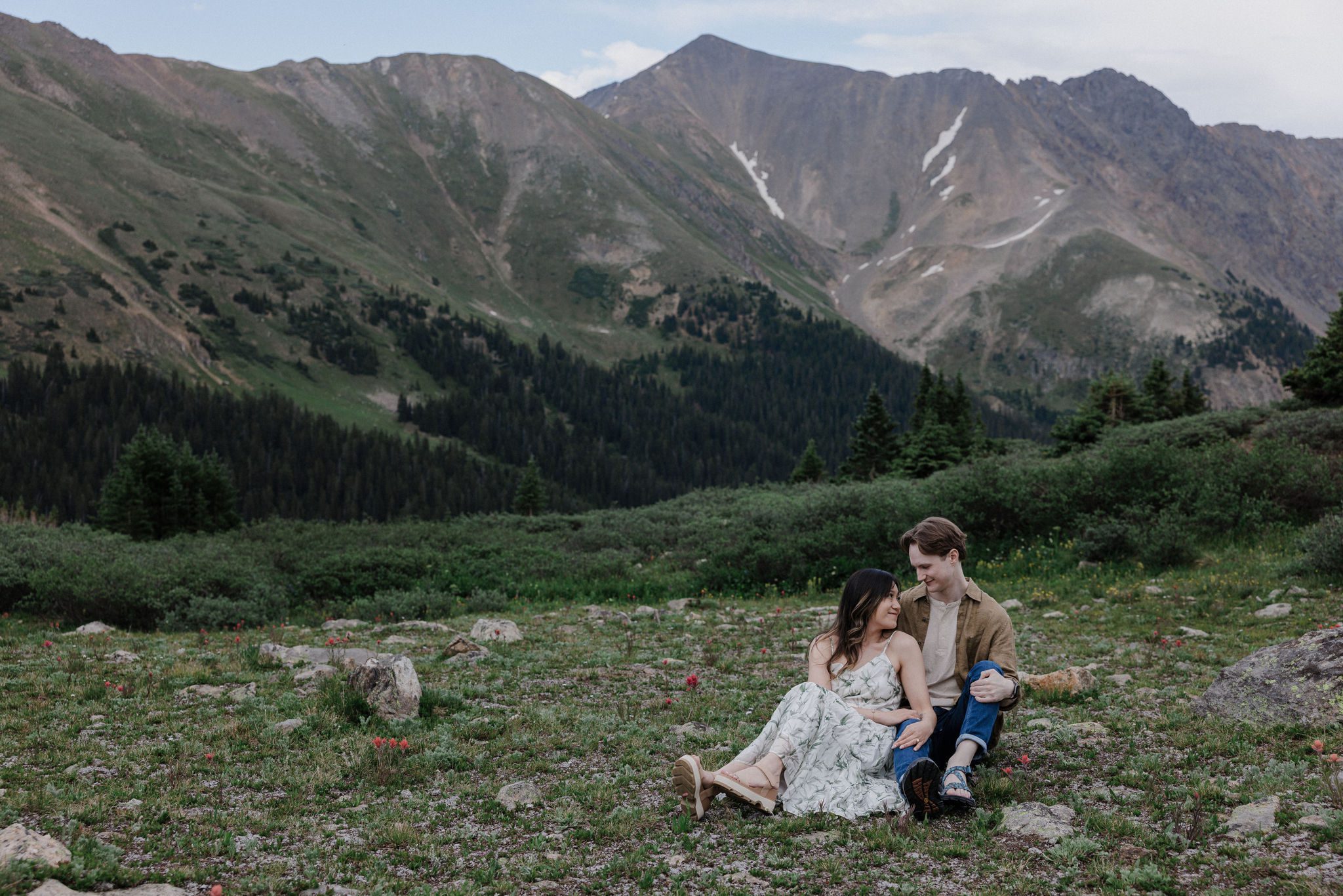 engaged couples sits in front of the colorado mountains during photo shoot