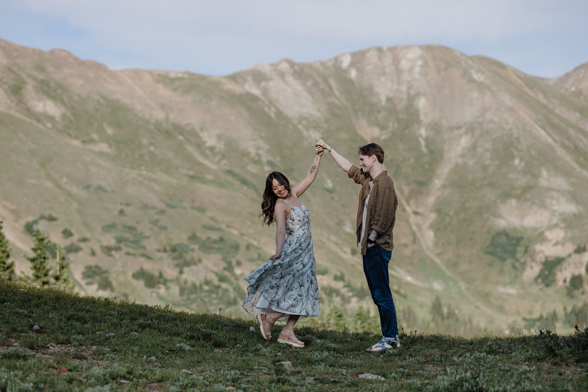 engaged couples dances in front of the colorado mountains during photo shoot