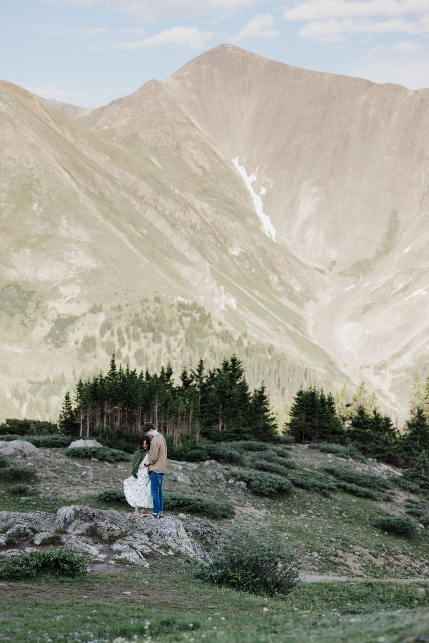 engaged couple dances in front of the colorado mountains during couples photo shoot