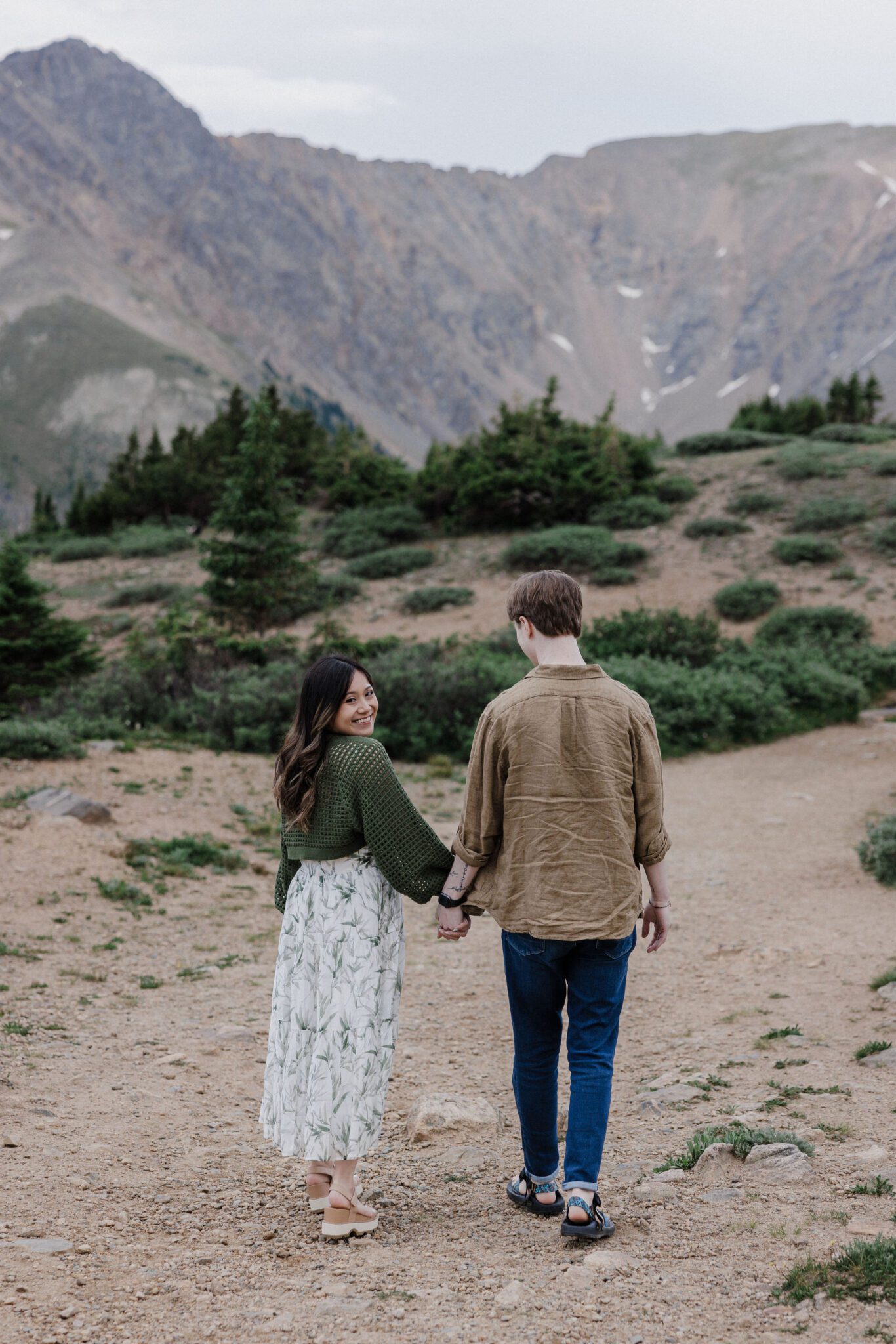 man and woman walk along trail during colorado engagement photos