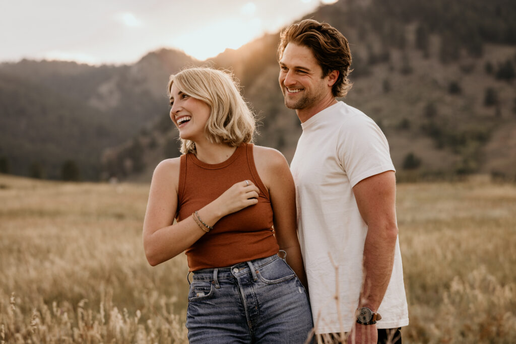 man and woman smile as they take engagement photos in colorado.