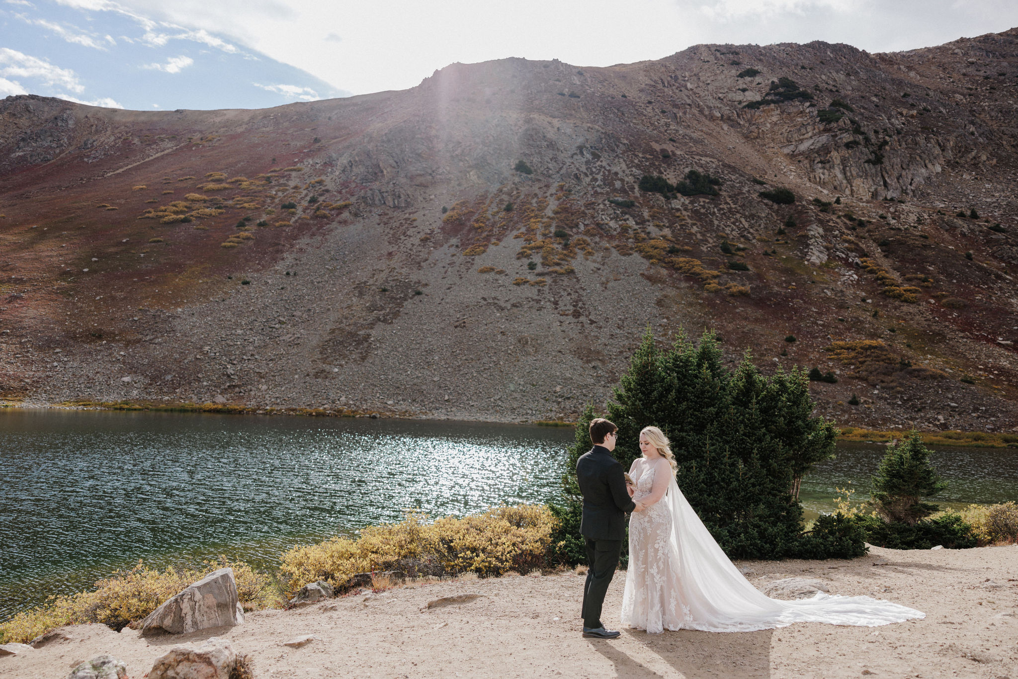 bride and groom stand by alpine lake during colorado wedding