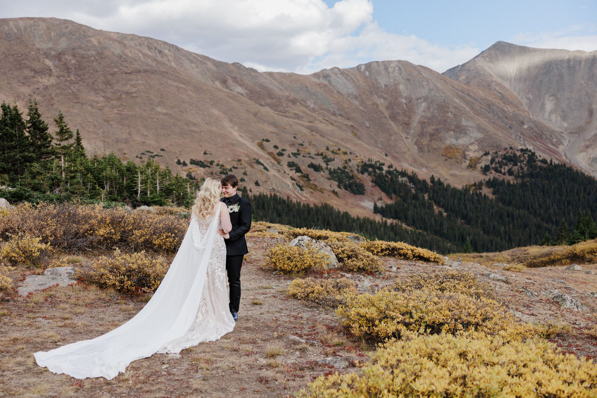 bride and groom stand in the colorado mountains during wedding ceremony by elopement planner