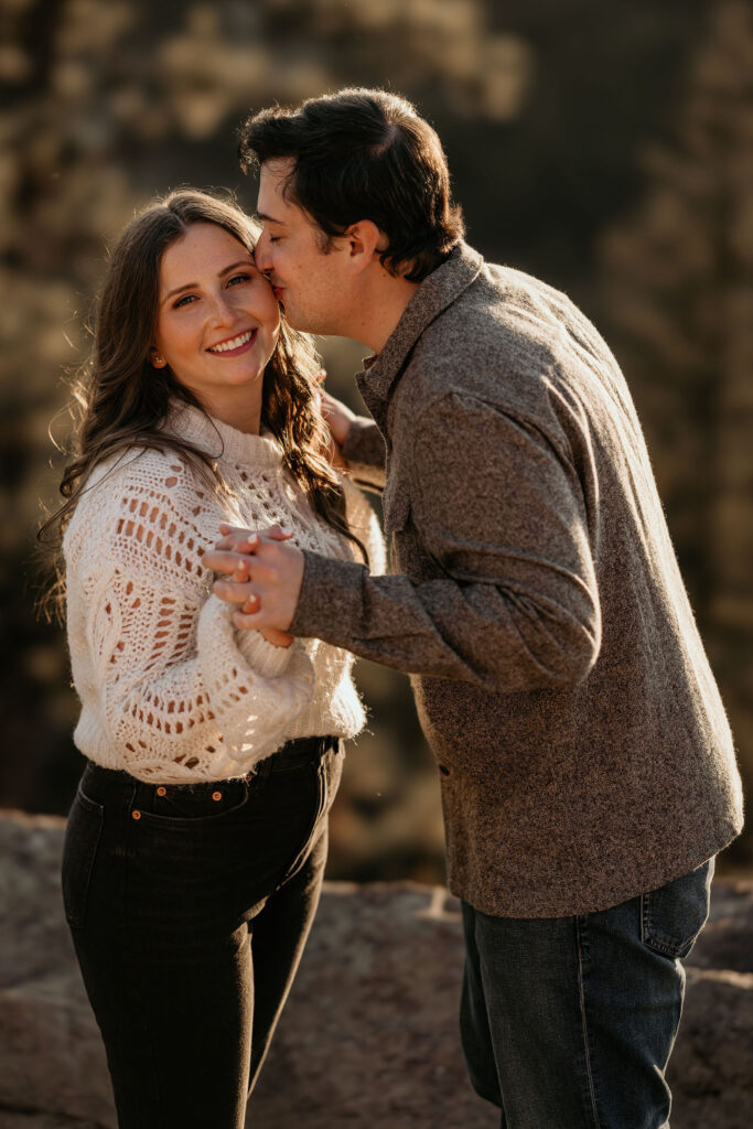 man kisses womans cheek during colorado mountain engagement photos.
