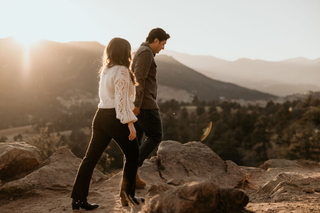 man and woman walk along trail during colorado mountain engagement photos.