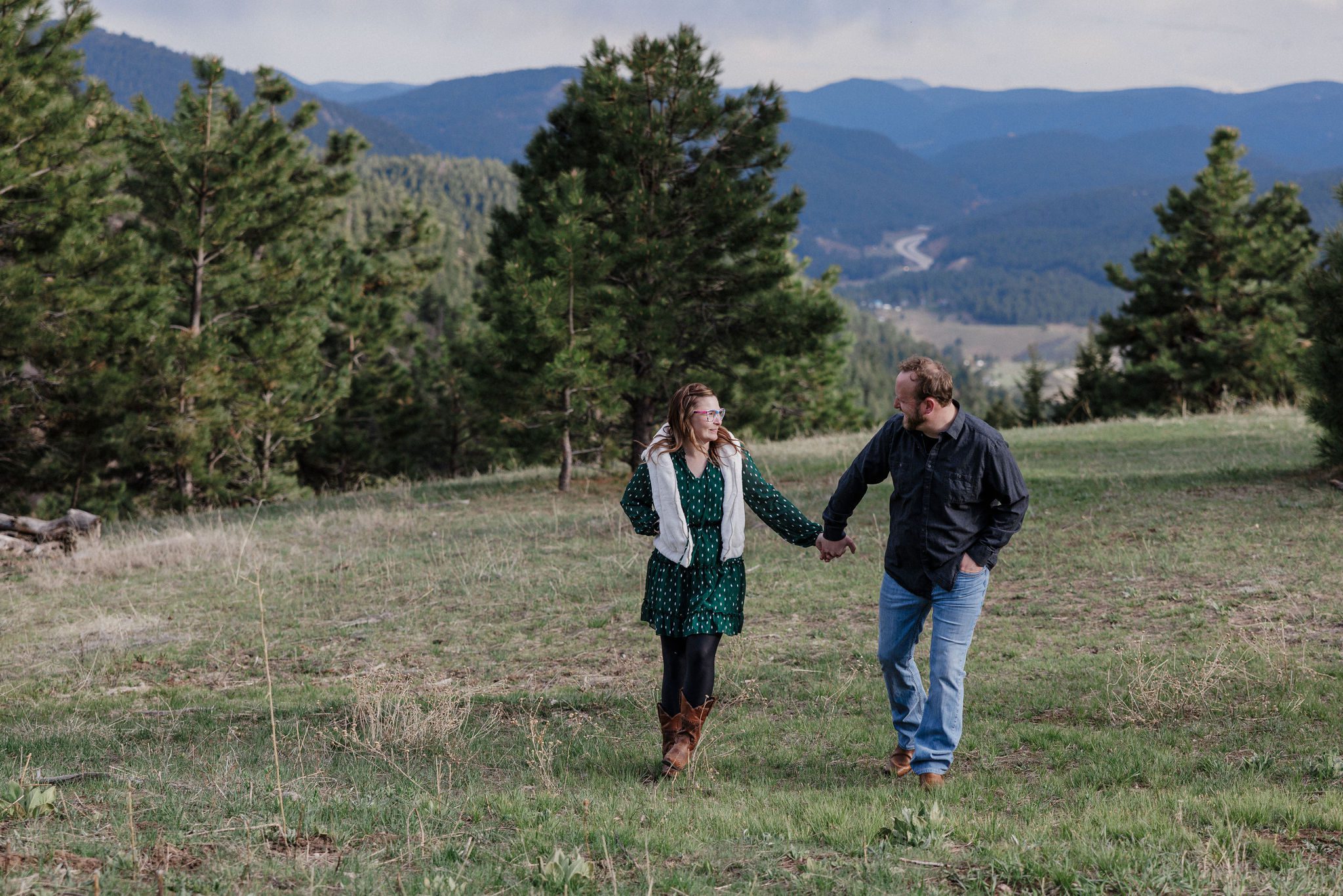 man and woman hold hands and walk during colorado engagement photos