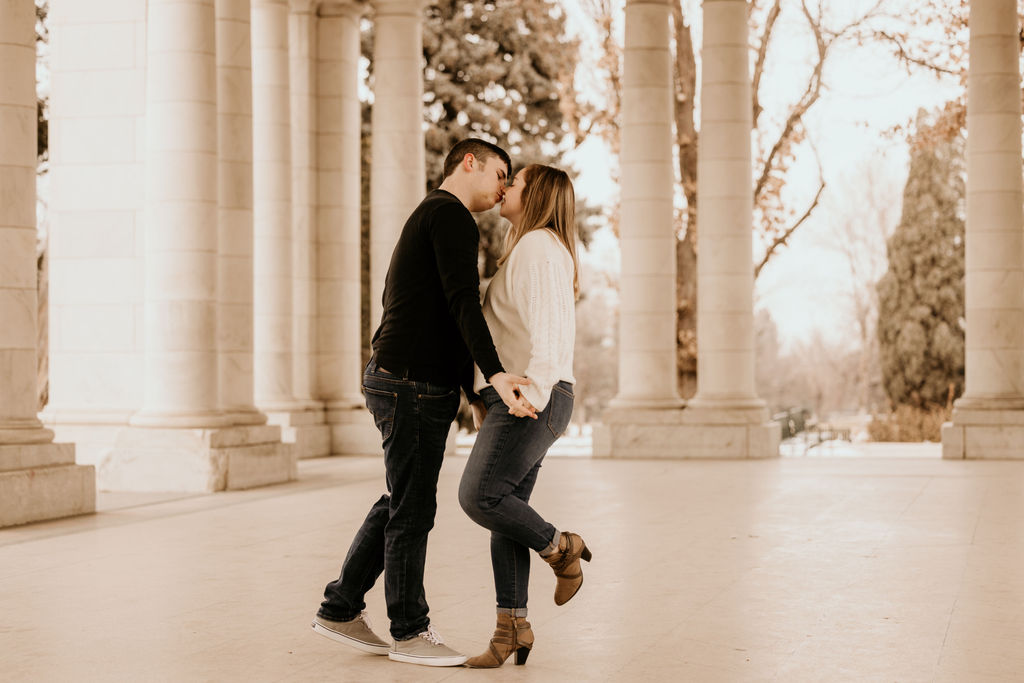 man and woman kiss in marble structure during denver couples portraits.