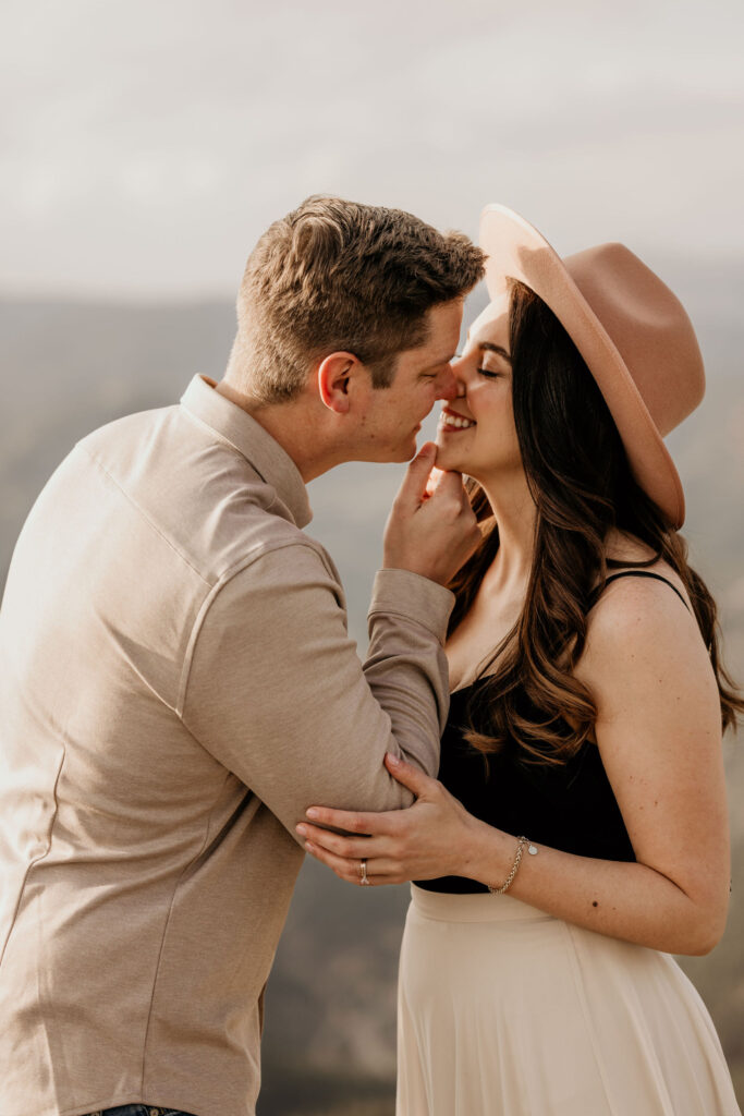 man leans in to kiss woman during colorado engagement photos.