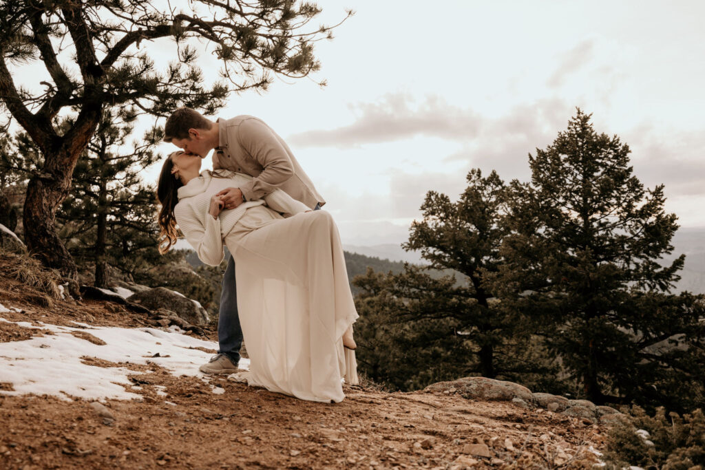 man dips and kisses woman during colorado engagement photos.