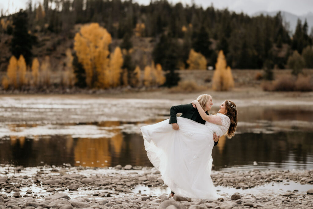 LGBTQ+ pose for colorado engagement photographer in front of aspen trees and a lake during colorado couples portraits.