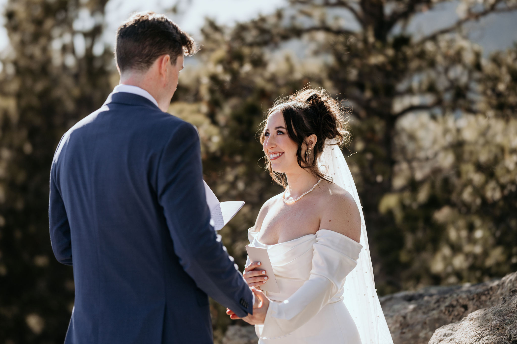 bride smiles up at groom as he says his wedding vows.