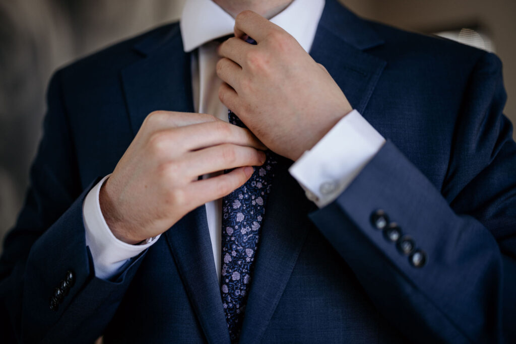 close up image of groom fixing his tie.