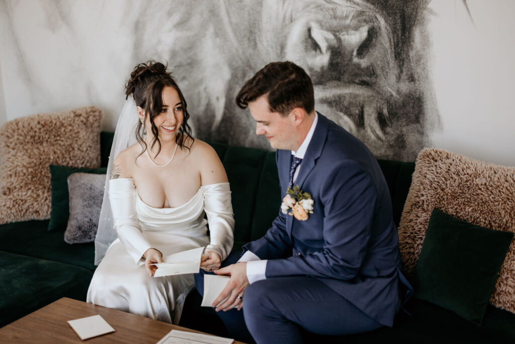 bride and groom smile as they read handwritten letters in an airbnb during colorado elopement day.