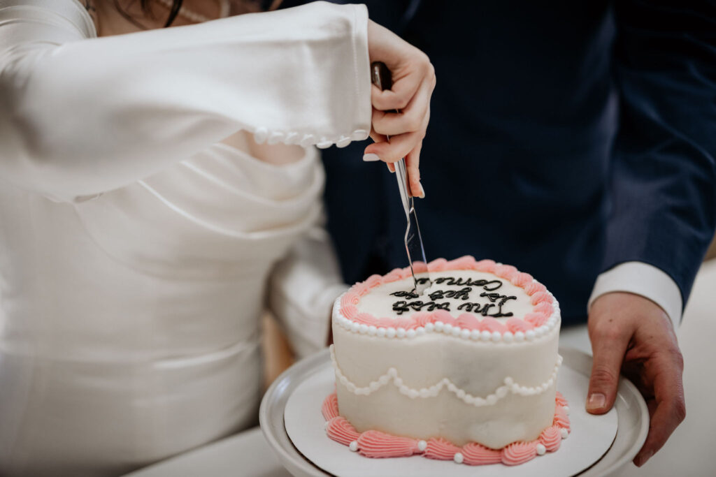 bride cuts vintage-style wedding cake during airbnb elopement.