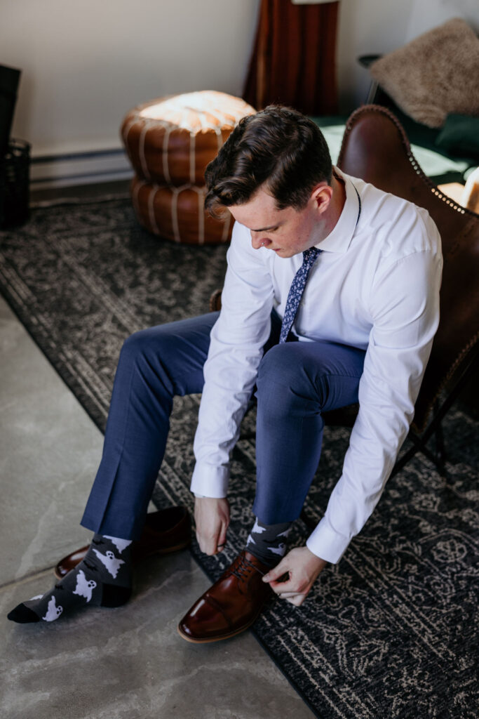 groom ties shoes while taking getting ready photos.