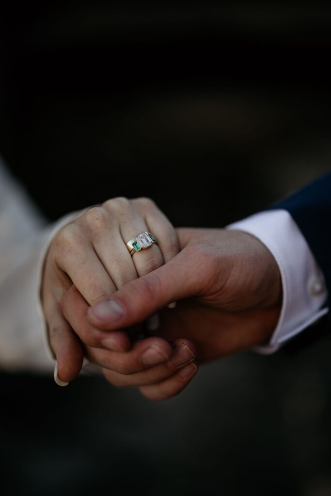 close up image of brides hand with wedding ring holding grooms hand.