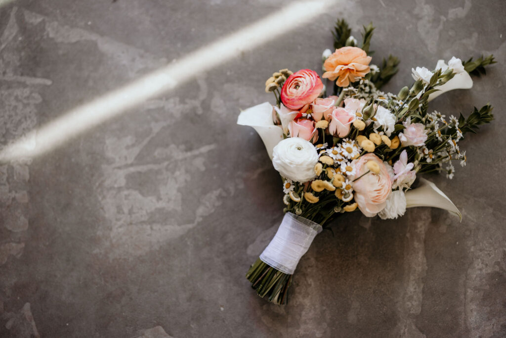 wedding bouquet lays on the concrete floor of an airbnb.