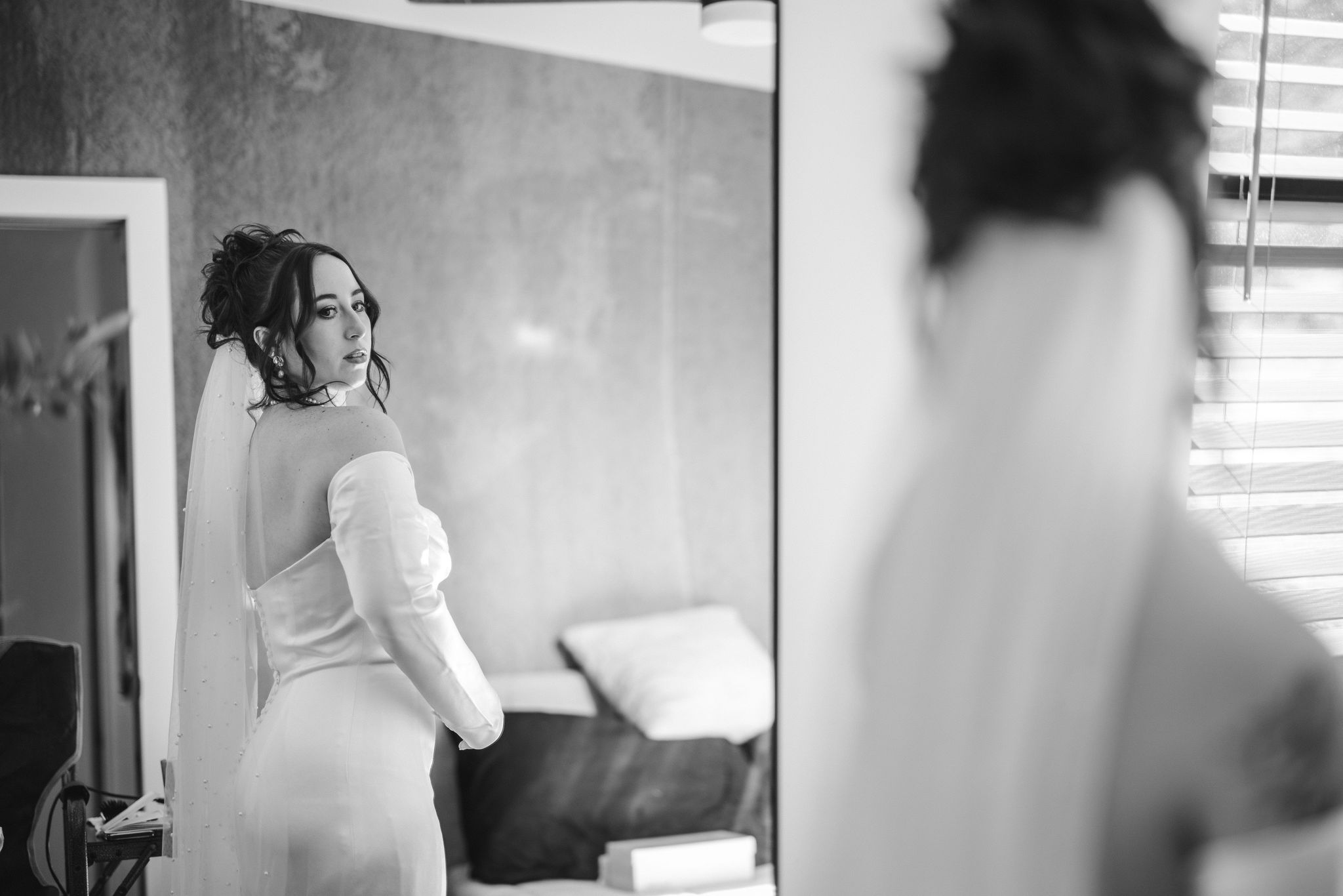 bride looks at herself in the mirror during airbnb elopement.