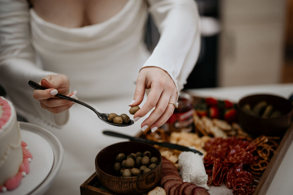 close up image of bride taking olives from a snack board during getting ready photos.