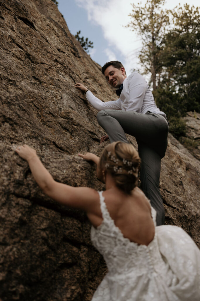 bride and groom climb rocks at rocky mountain national park during wedding day.