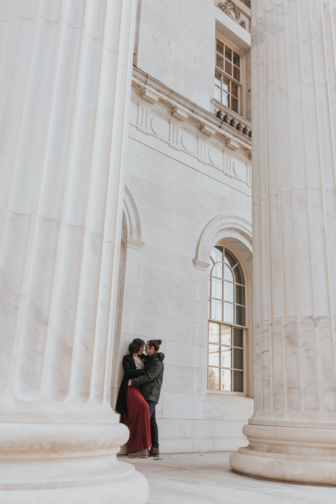man and woman lean against byron white courthouse during couples portraits.