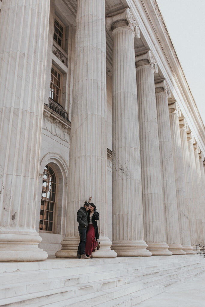 man and woman lean against columns during denver engagement photos.