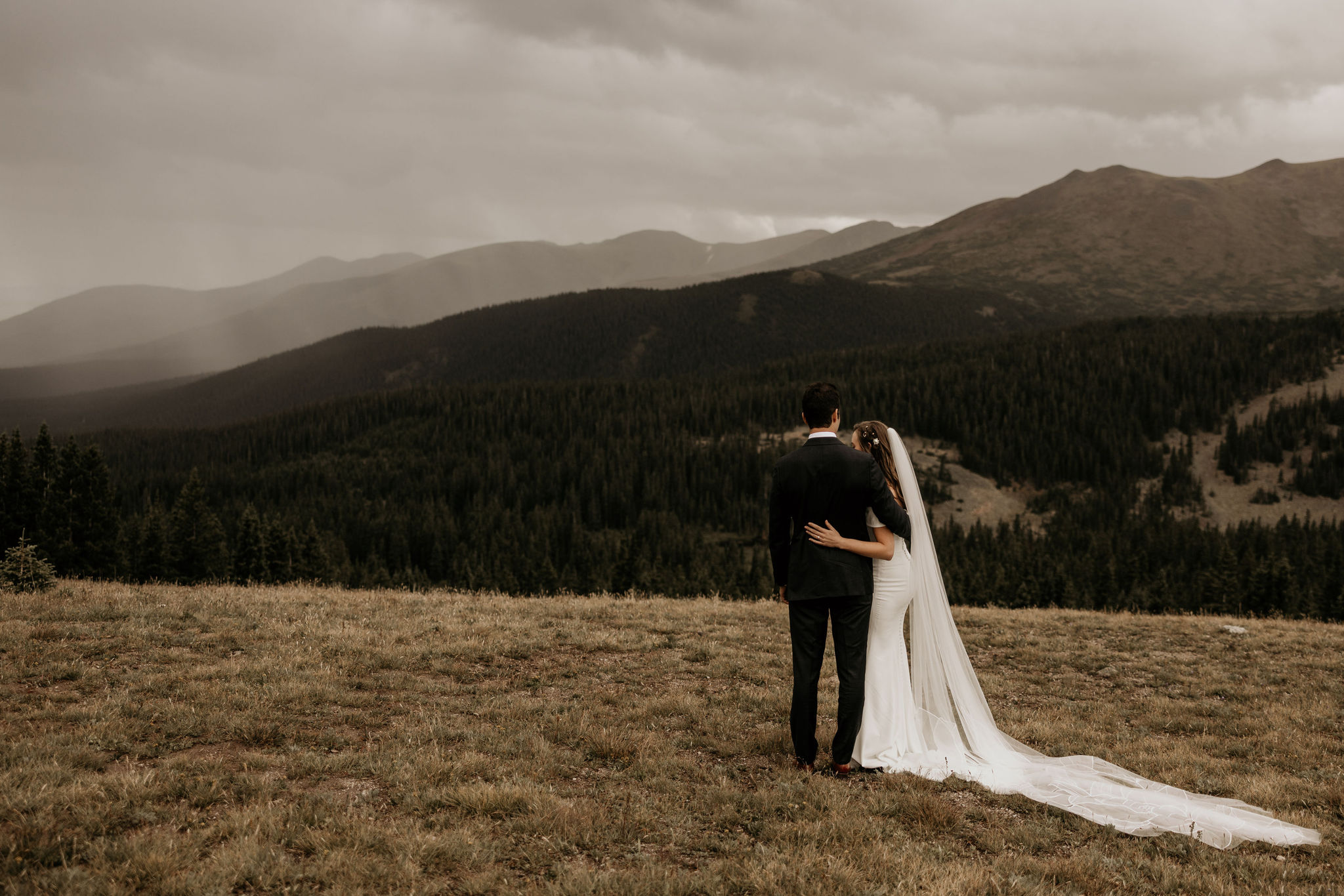 bride and groom embrace in front of the colorado mountains during elopement.