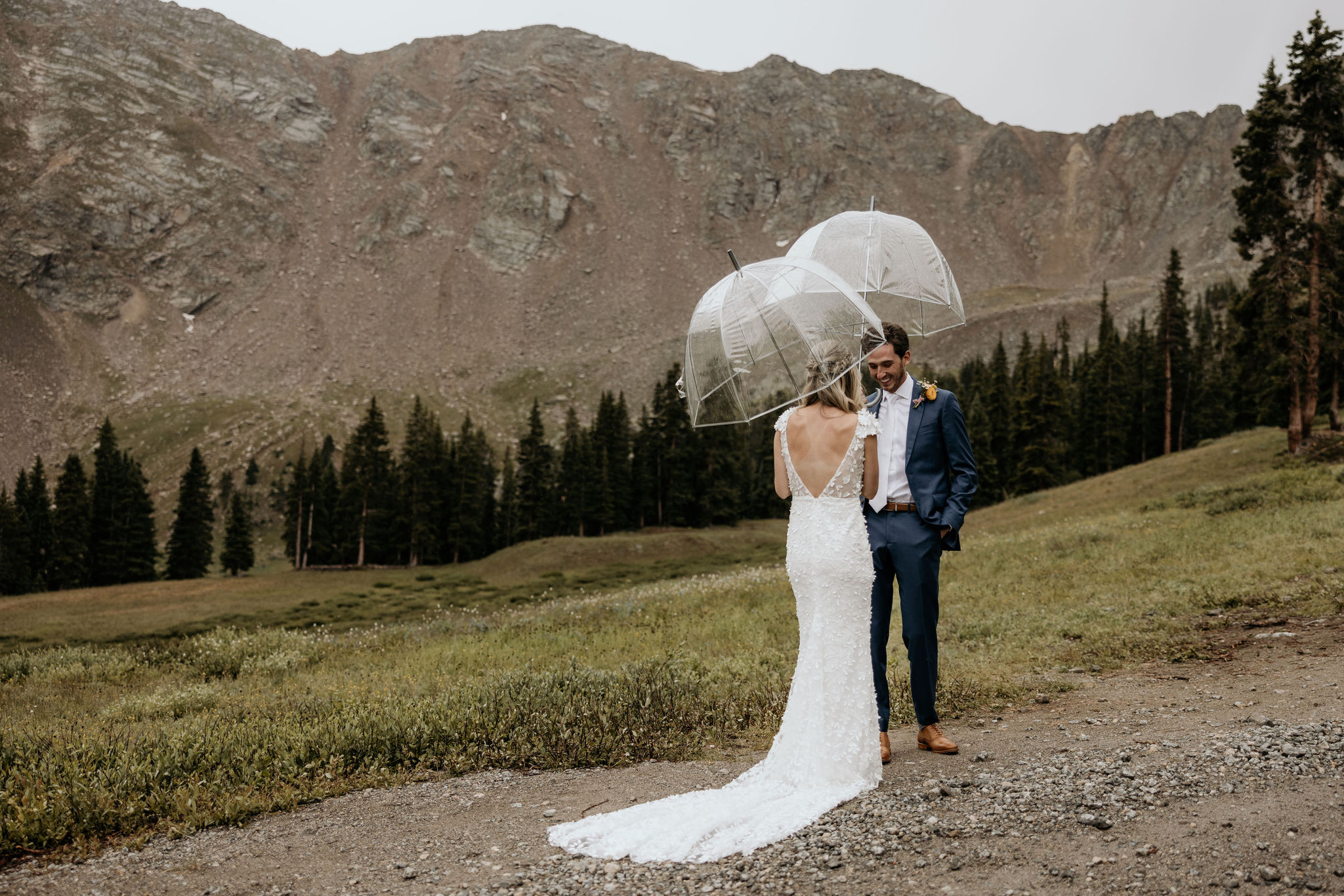 bride and groom hold umbrellas during wedding day first look in the mountains.