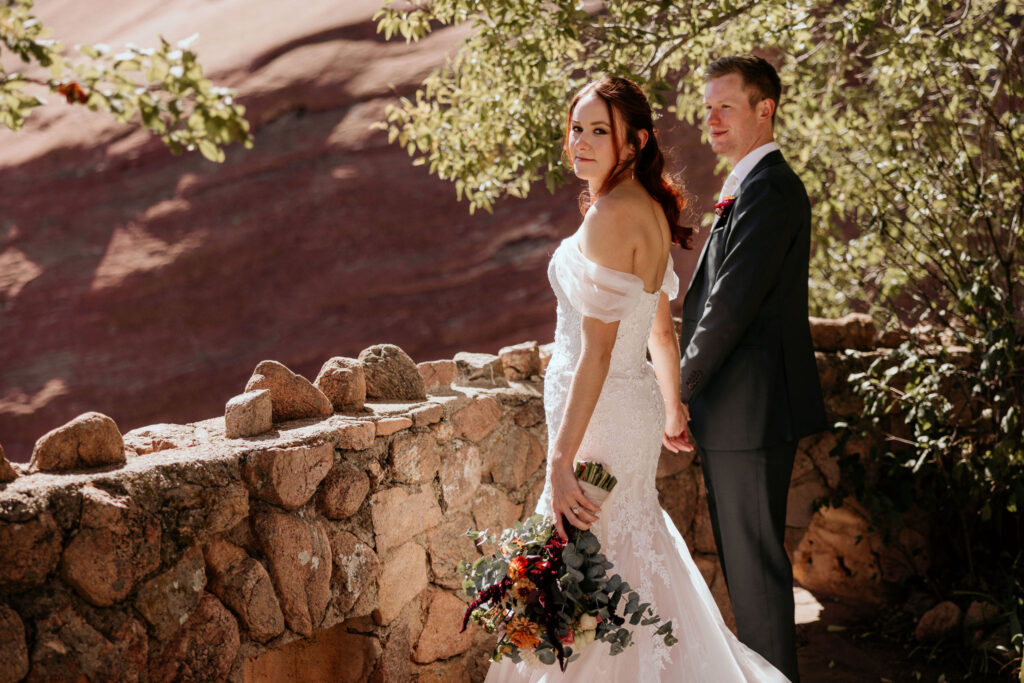 bride and groom hold hands and look at colorado micro wedding photographer.