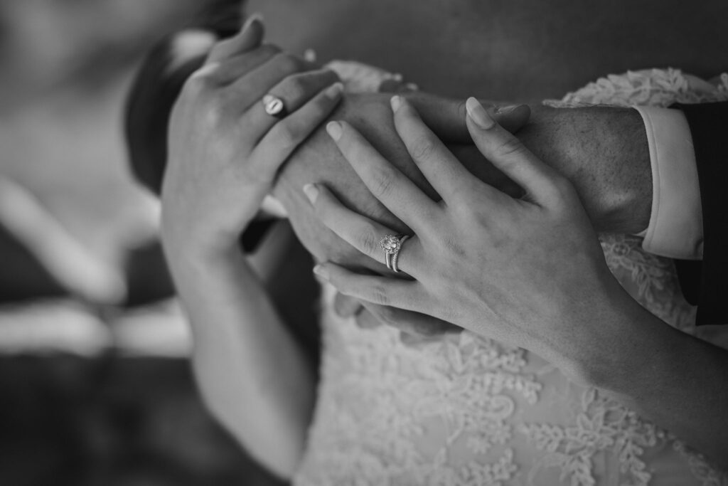 close up image of grooms hands wrapped around brides shoulders.