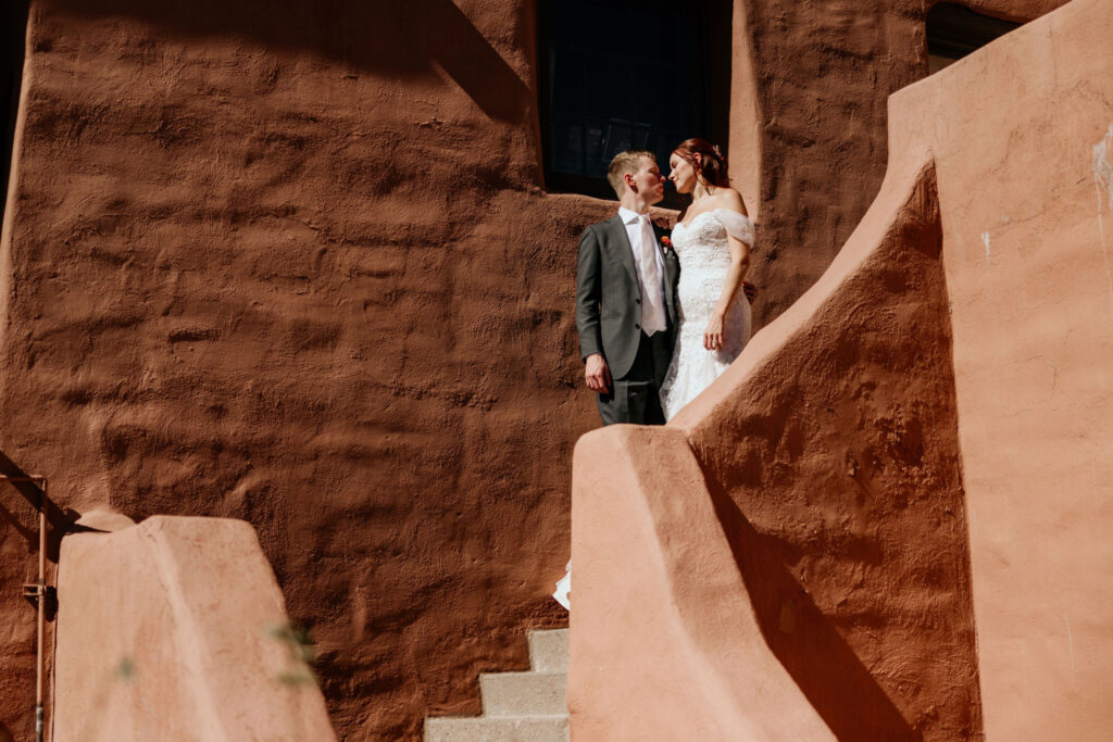 bride and groom stand on steps of southwest building during colorado micro wedding