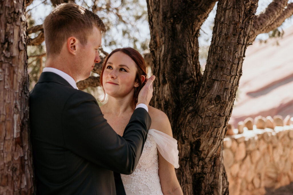 groom puts brides hair behind her ear.