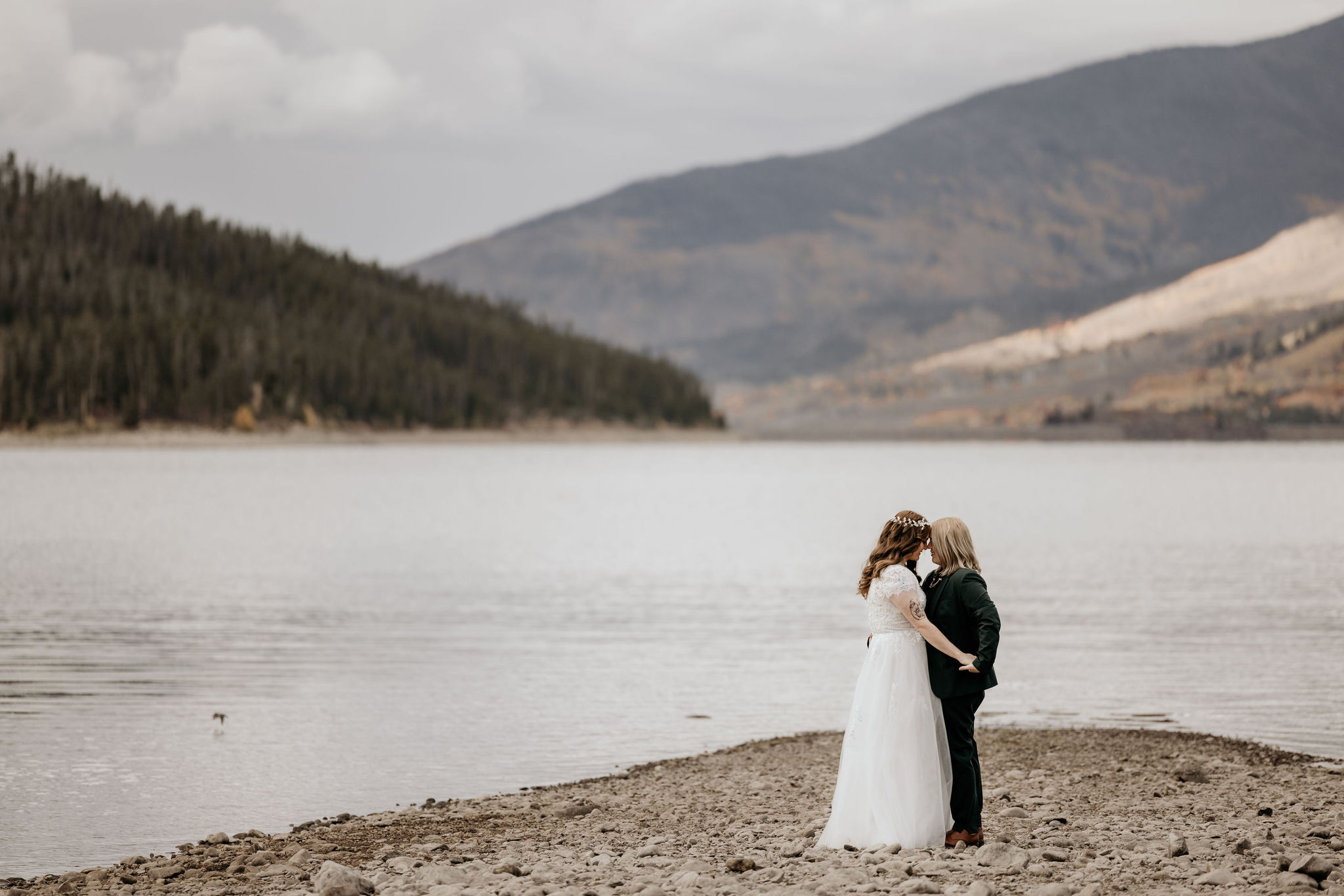 two brides embrace by lake during colorado elopement.