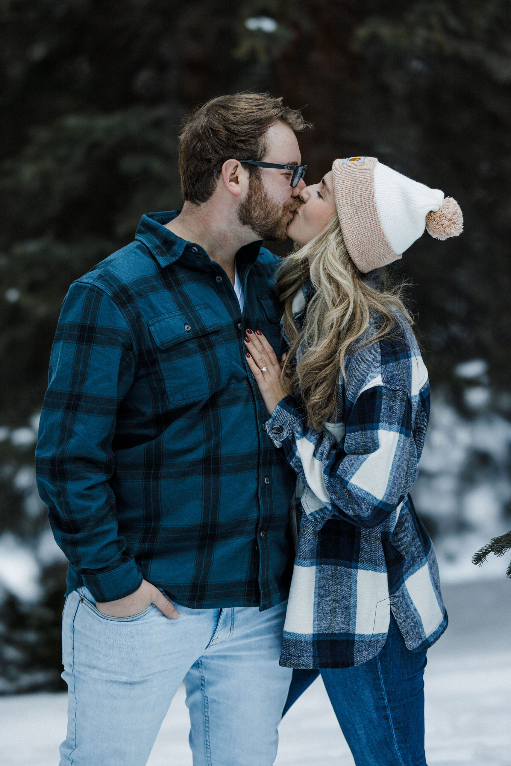 engaged couple kisses in the colorado forest.