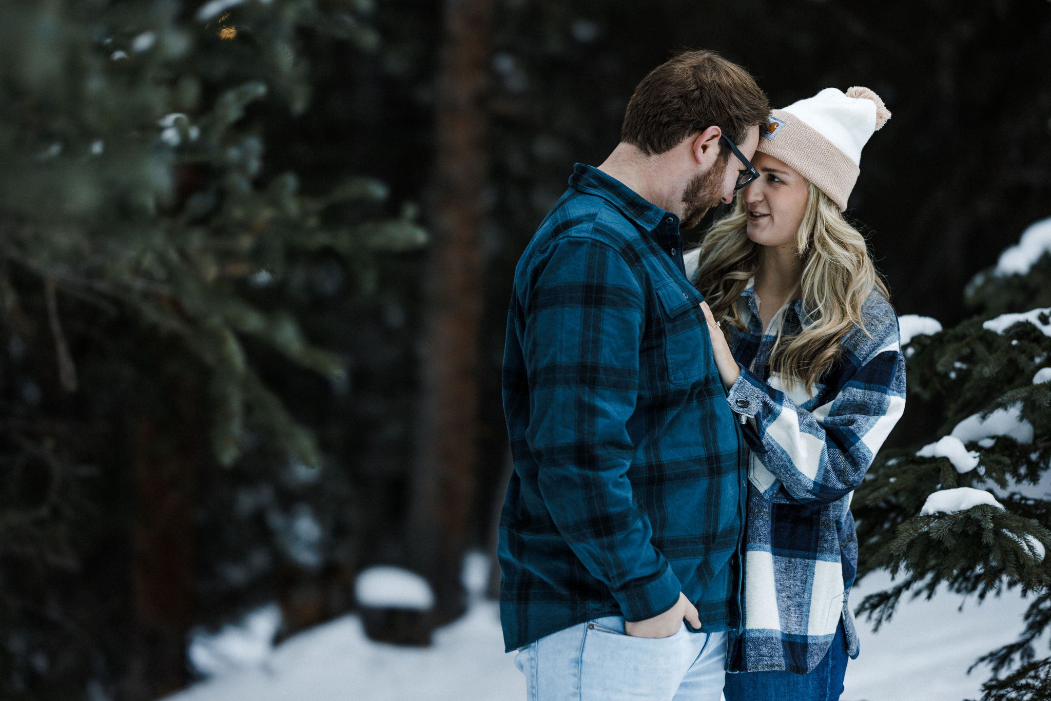 engaged couple poses for colorado engagement photographer on snowy trail.